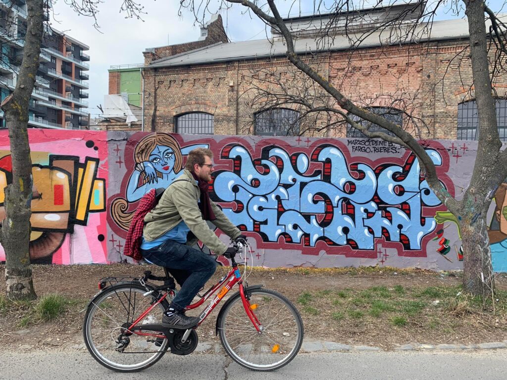Un ciclista frente a una pared con grafitis en una visita alternativa por Budapest