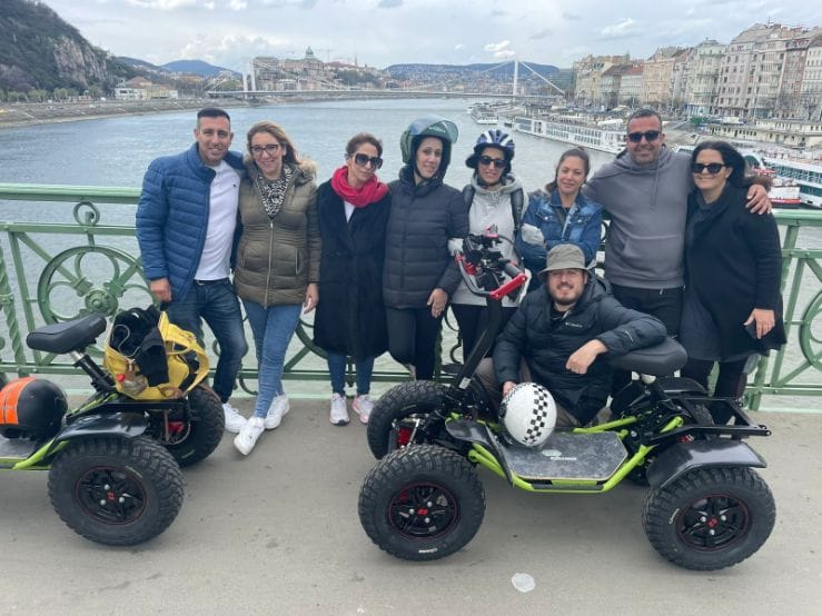 A group on an Easy Rider tour is taking a picture on a bridge over the Danube River in Budapest