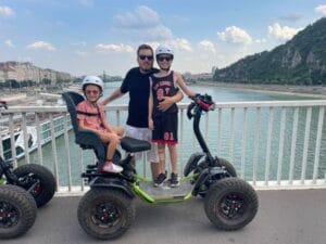 A father and two children are riding an Easy Rider on a bridge over the Danube