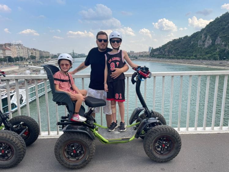 A father and two children are riding an Easy Rider on a bridge over the Danube